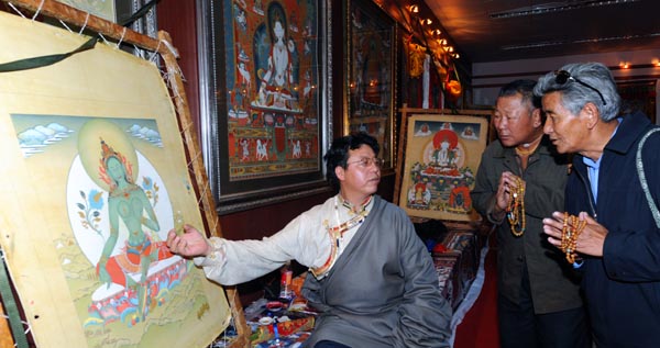 8月6日，西藏拉姆拉绰艺苑画师丁嘎在西藏博物馆向前来参观的信徒讲解他的创新唐卡绘画作品。
